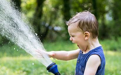 boy playing with water coming out of hose